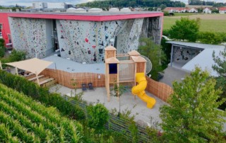 Außenansicht der Halle mit Outdoorbereich und Spielplatz