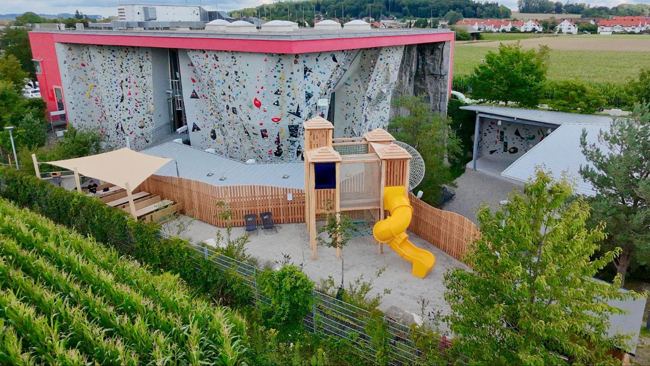 Außenansicht der Halle mit Outdoorbereich und Spielplatz
